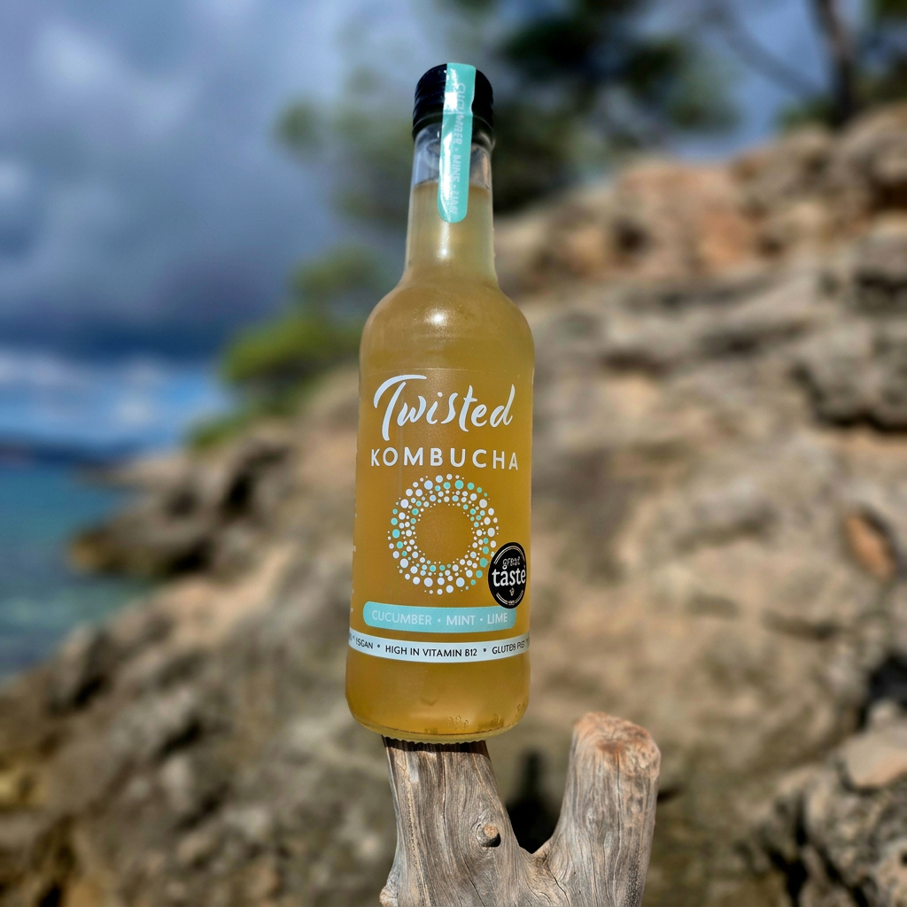 Cucumber, Mint & Lime kombucha bottle on driftwood at the beach, 