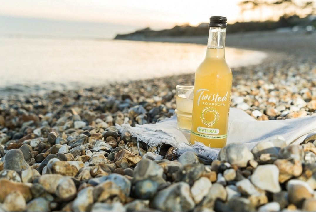 Bottle of Twisted Lemonade on a pebbly beach with a scenic background